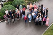 Eine Gruppe aus Frauen und Männern stehen auf einem Weg und schauen nach oben in die Kamera. 