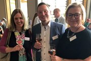 Zwei Frauen und ein Mann posieren mit einem Glas Wein vor der Kamera. 