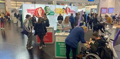 Zahlreiche Menschen informieren sich an einem Messestand mit Aufstellern der bbw-Gruppe.