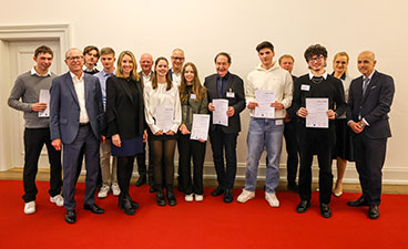 Eine Gruppe von Schüler*innen steht vor einer Wand und hält ihre Urkunde in die Kamera.