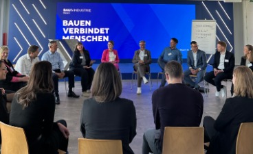 Abschluss des Wirtschaftsvolontariats 2025. Mehrere Menschen sitzen in einem Stuhlkreis und tauschen sich aus.