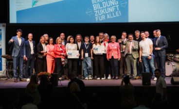 Personengruppe steht auf einer Bühne und posiert für ein Foto.